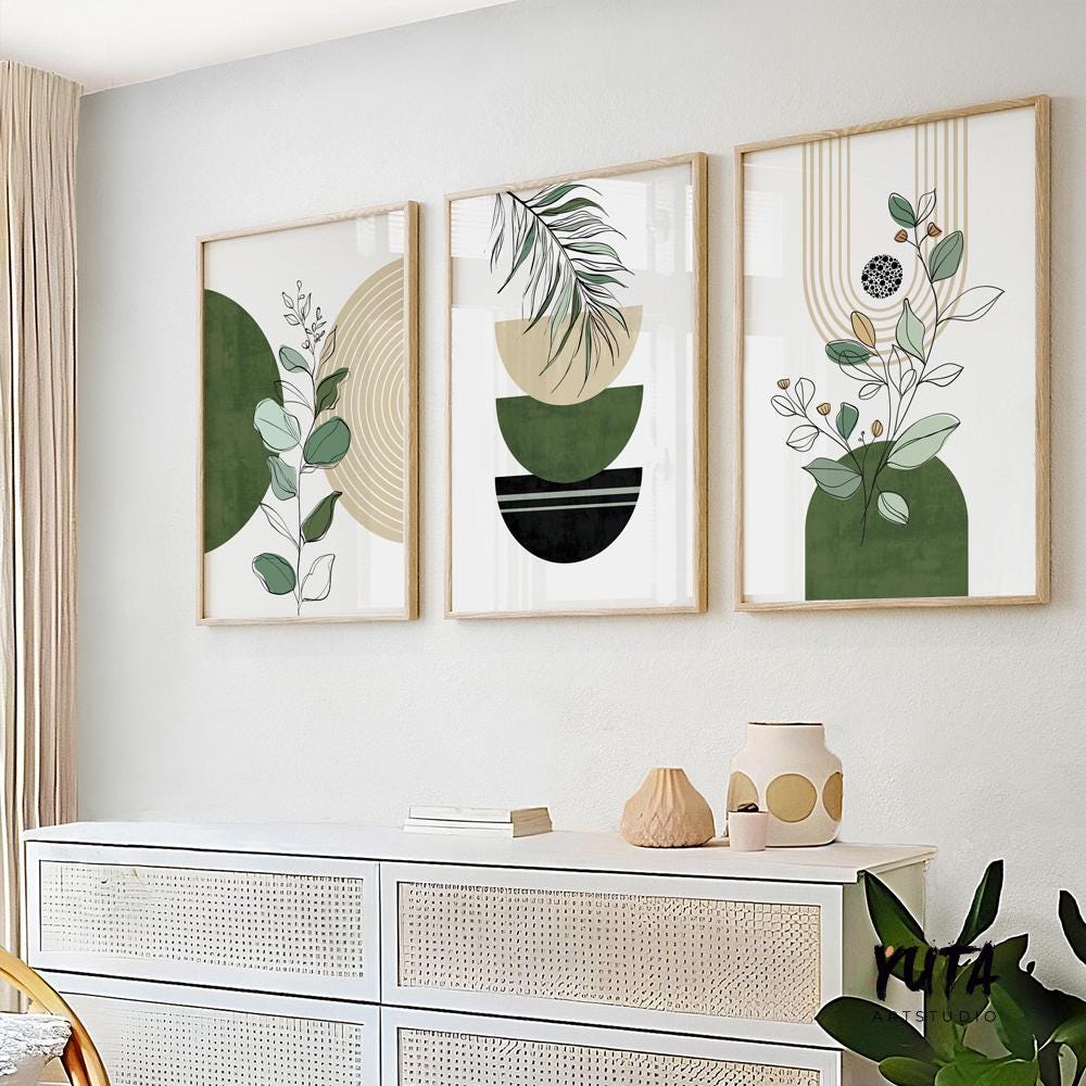 Three framed abstract green and black botanical prints in a vertical arrangement above a white sideboard.