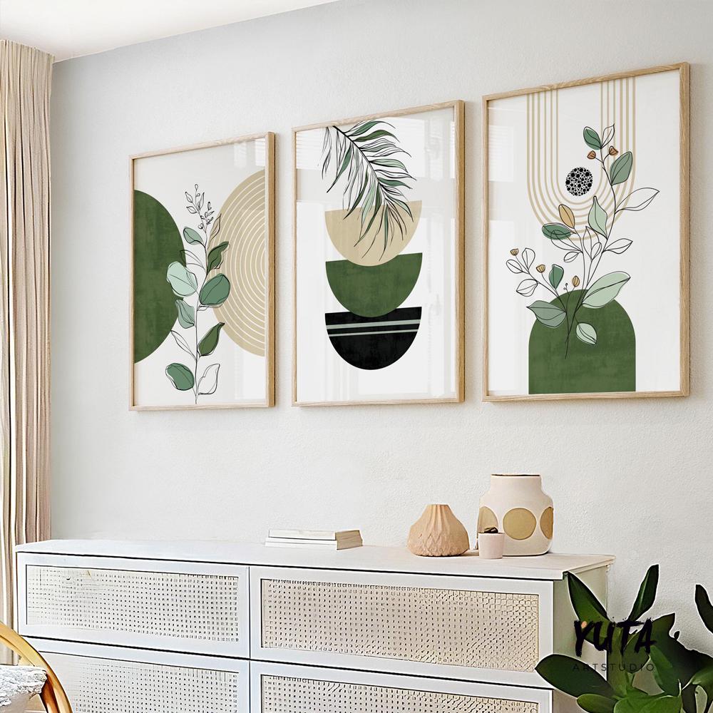 Three framed botanical abstract prints in green and beige arranged above a white sideboard