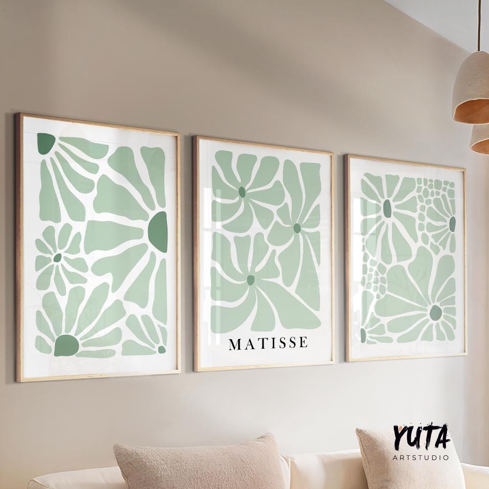 Sage green abstract floral prints in natural wood frames above a console table