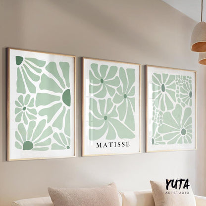 Sage green abstract floral prints in natural wood frames above a console table