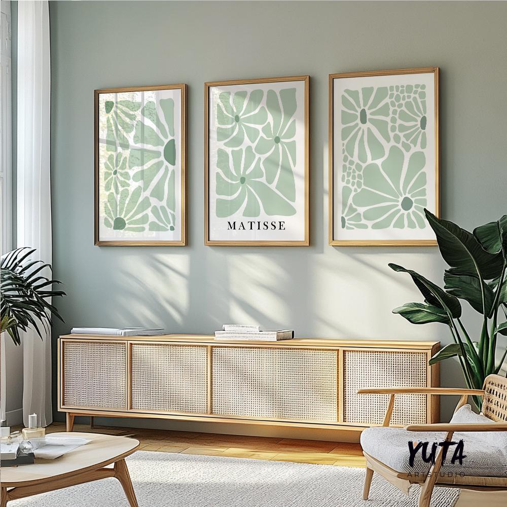 Three minimalist sage green floral prints in oak frames sized above a low console