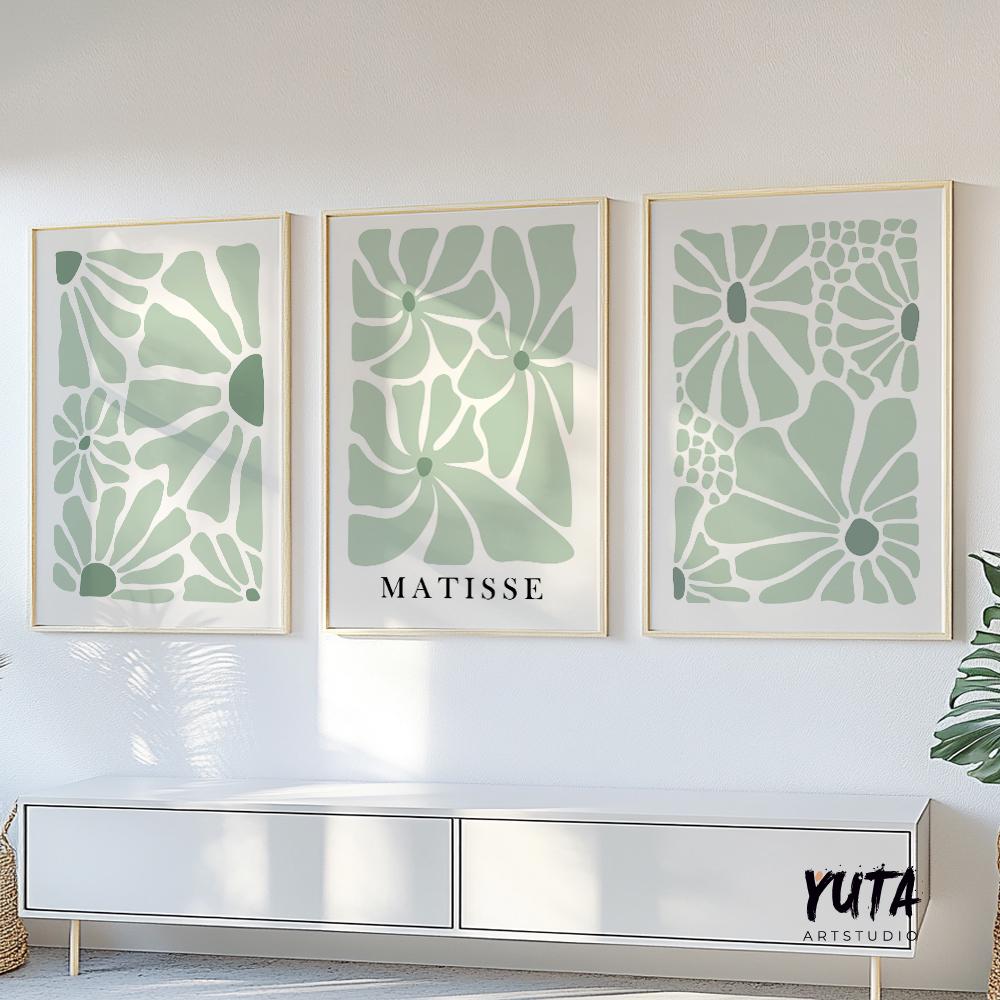 Three minimalist sage green floral prints in thin gold frames arranged above a white console
