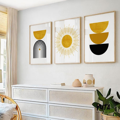 Trio of framed mustard yellow and black abstract prints above a sideboard in sunlit room