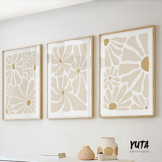 Neutral abstract floral prints in light wood frames arranged in a row above a white console
