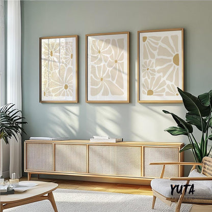 Three beige abstract floral prints in light wood frames on a sunlit gallery wall.