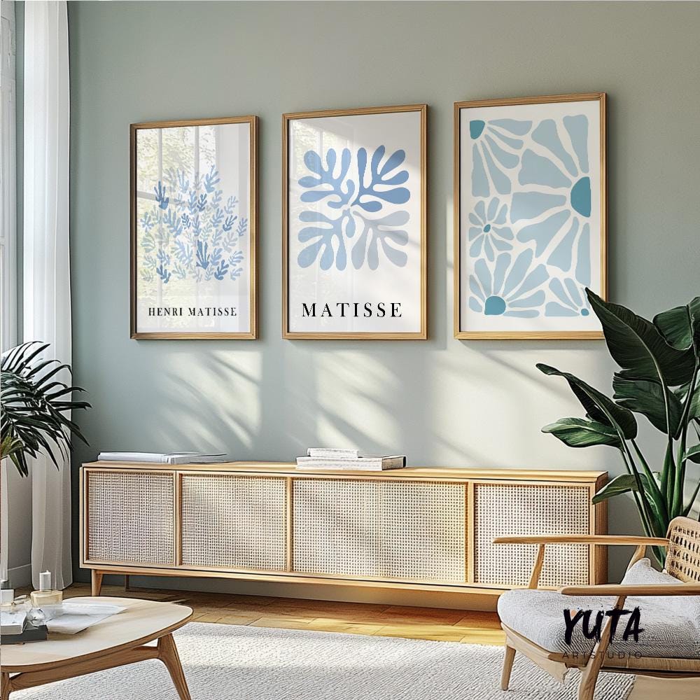 Trio of blue Matisse-style abstract prints in light wood frames above a woven sideboard
