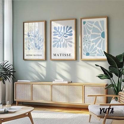 Trio of blue Matisse-style abstract prints in light wood frames above a woven sideboard