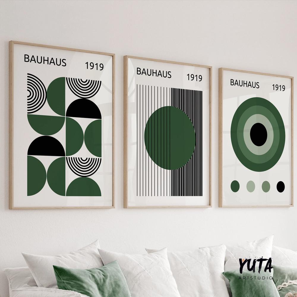 Trio of framed Bauhaus art prints in green and black above a white sofa with a green pillow.