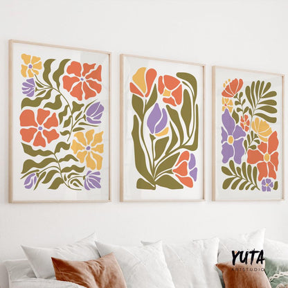 Three framed Matisse-inspired floral prints in bold colors arranged above a white sofa
