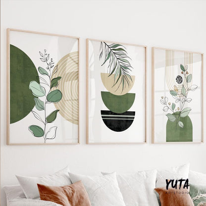 Trio of green and black boho prints in light wood frames displayed above a white sofa