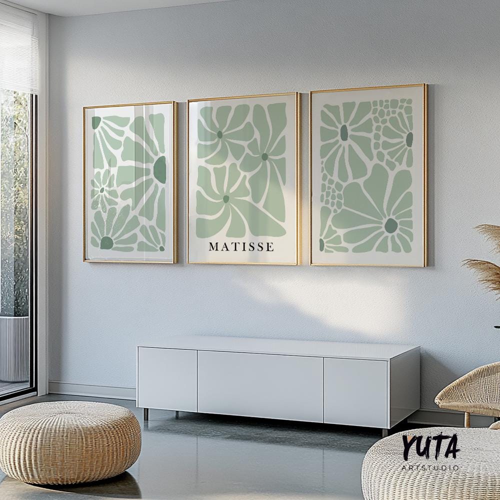 Sage green Matisse-inspired floral prints in gold frames arranged above a white console