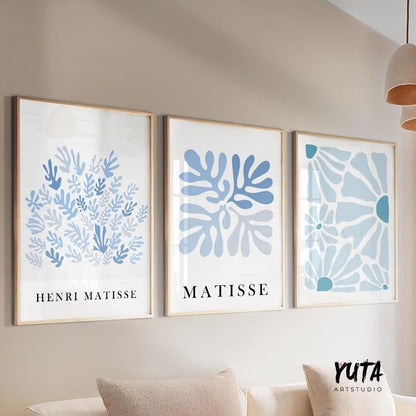 Three mid-century blue Matisse prints in light wood frames arranged above a sofa