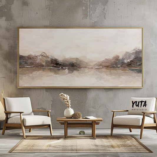 Panoramic abstract landscape in soft beige tones framed above a table with dried plants and books