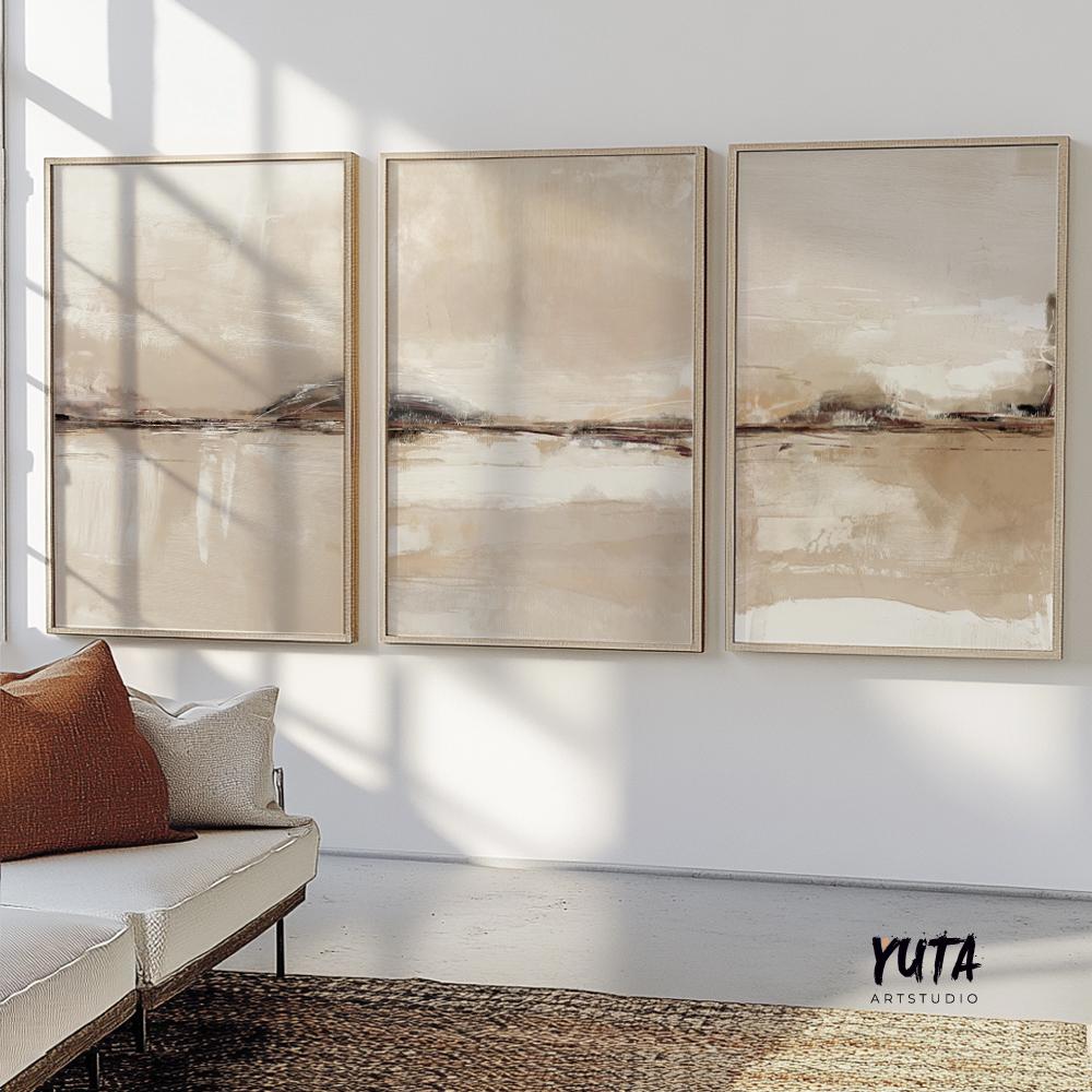 Framed neutral abstract triptych above a white sofa with a brown cushion and woven rug