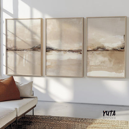 Framed neutral abstract triptych above a white sofa with a brown cushion and woven rug