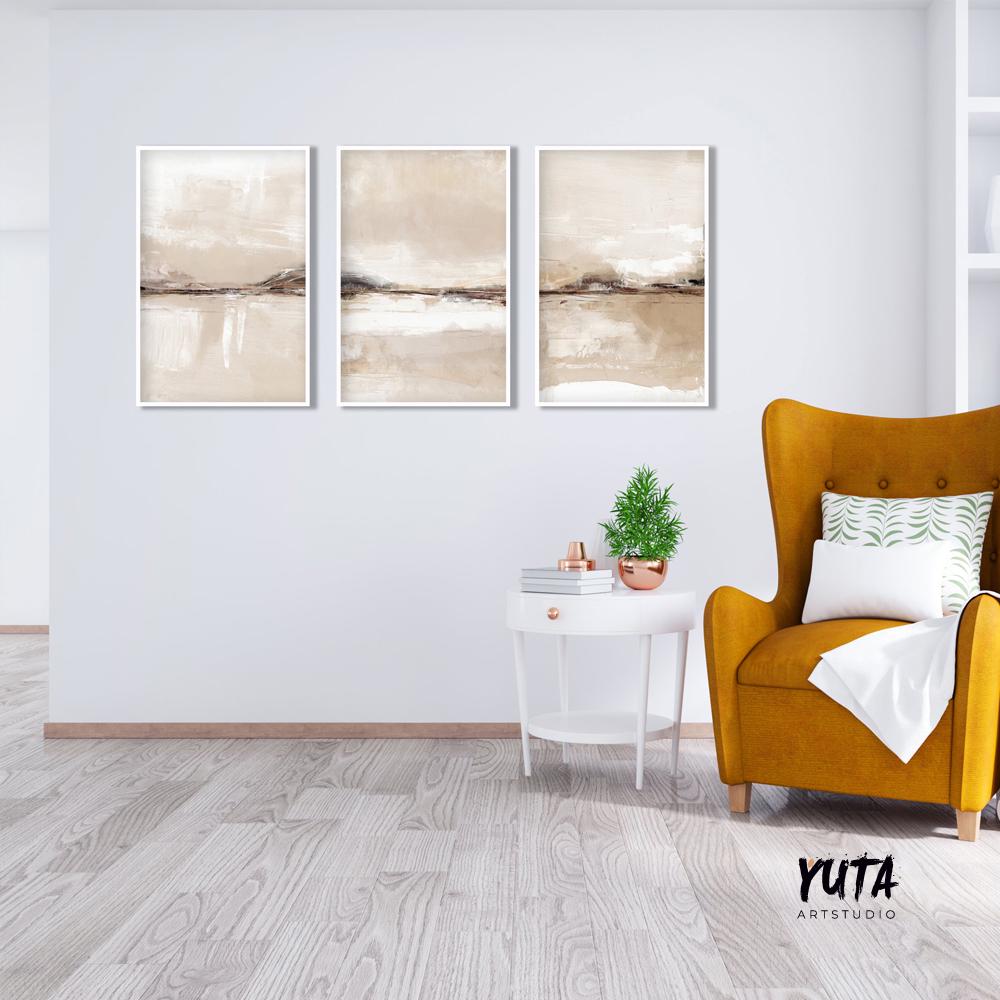 Neutral abstract art triptych in white frames displayed above a white accent table.