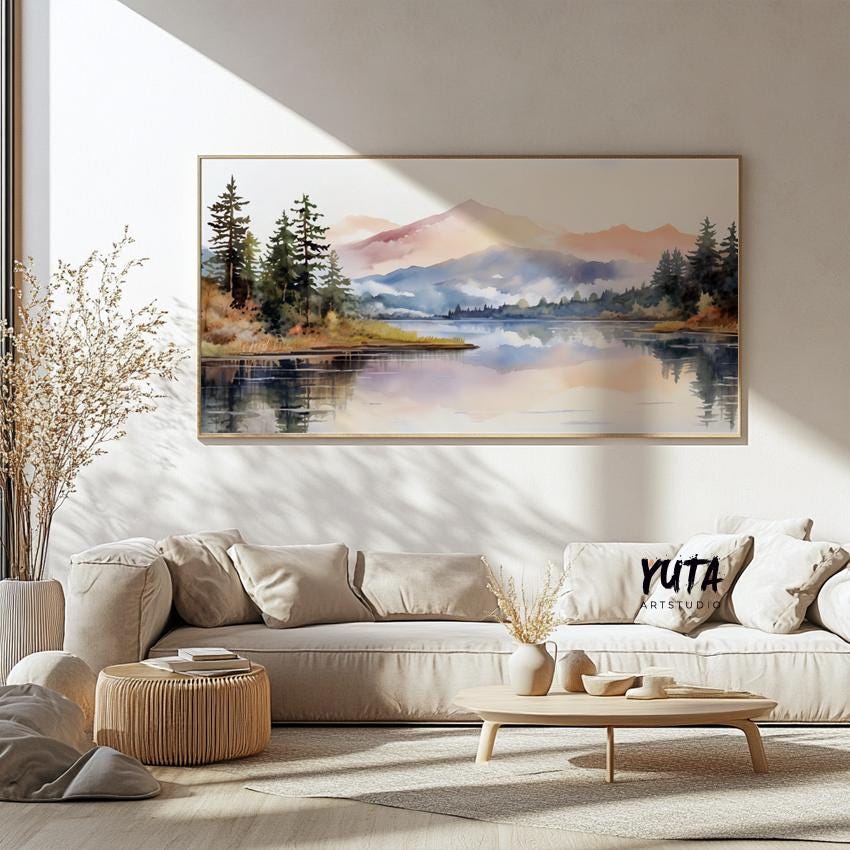 Framed pastel mountain landscape art above a neutral sofa, styled with ceramics and dried plants