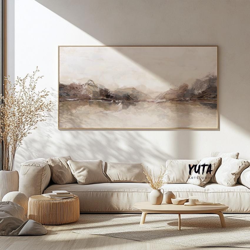 Neutral panoramic abstract print in soft beige tones, framed and centered above a cream sofa