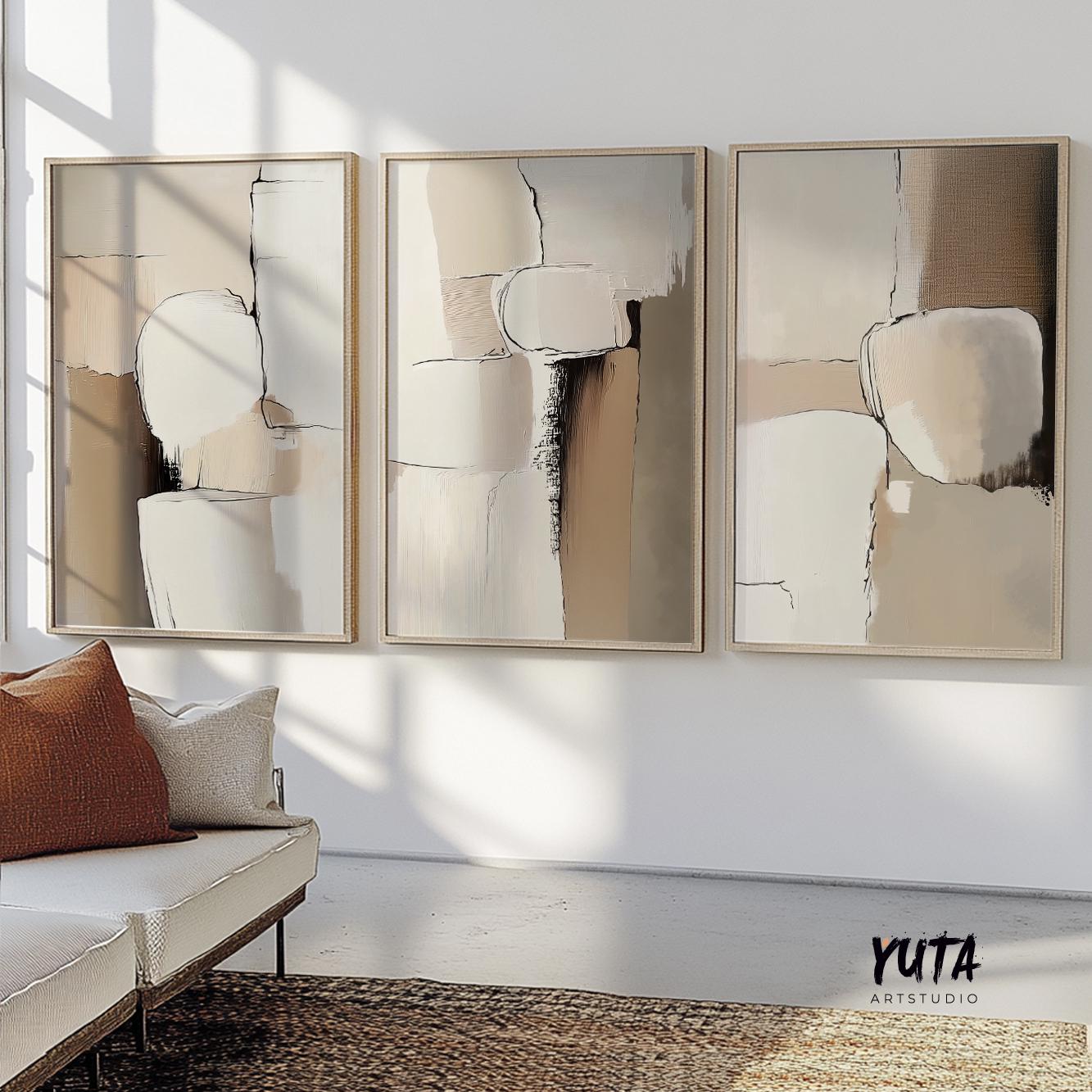Neutral abstract art trio in light wooden frames arranged above a modern cream sofa