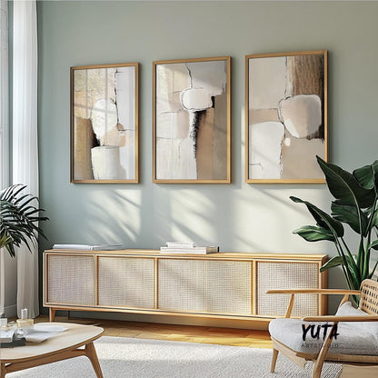 Abstract earth tone paintings in light wood frames arranged above a caned sideboard