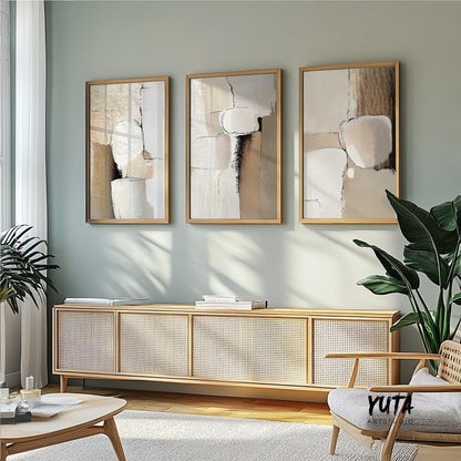 Set of three abstract earth tone prints in wood frames displayed above a woven bench