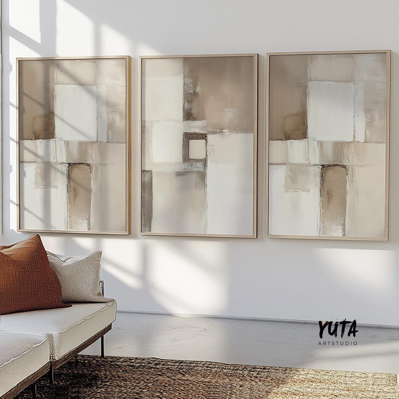 Neutral abstract brushstroke artwork in natural wood frames, set of three above a sofa