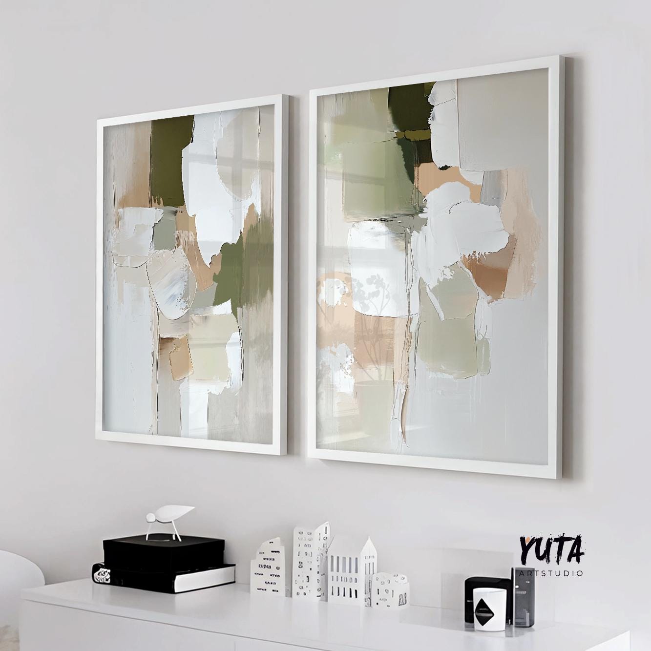 Two framed pastel green and beige abstract prints hung side by side above a white console in daylight