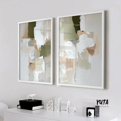Two framed pastel green and beige abstract prints hung side by side above a white console in daylight
