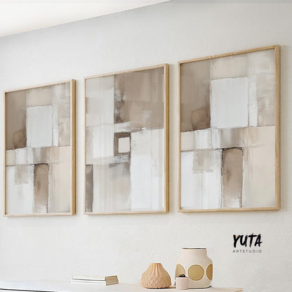 Neutral abstract brushstroke triptych in light wood frames arranged in a linear gallery row