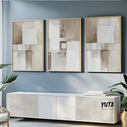 Three neutral abstract brush stroke prints in light wood frames above a modern console