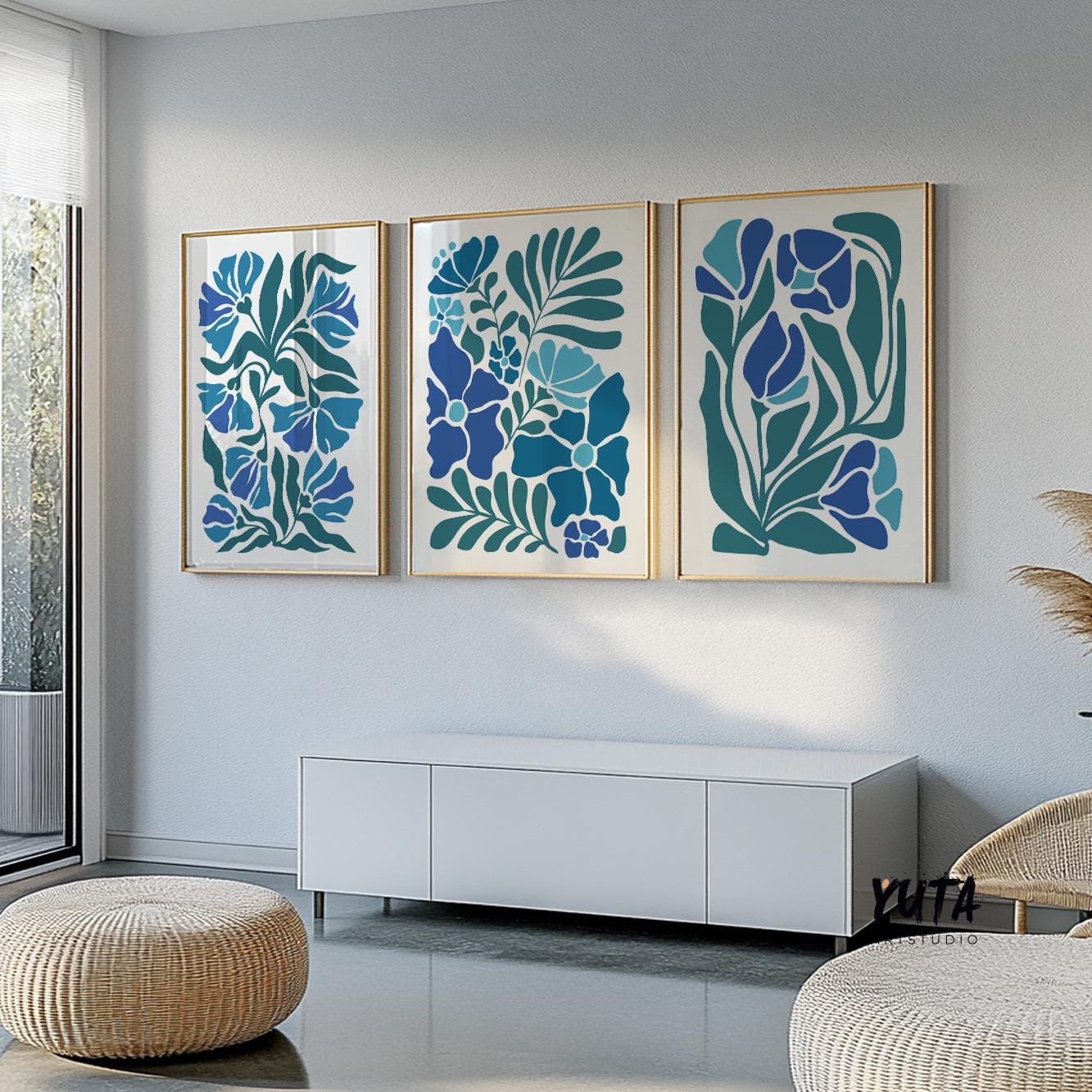 Three mid-century floral prints in gold frames arranged above a low white cabinet