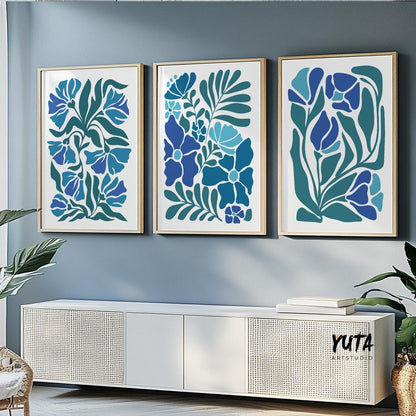 Three framed abstract floral prints in blue tones displayed above a white console in daylight