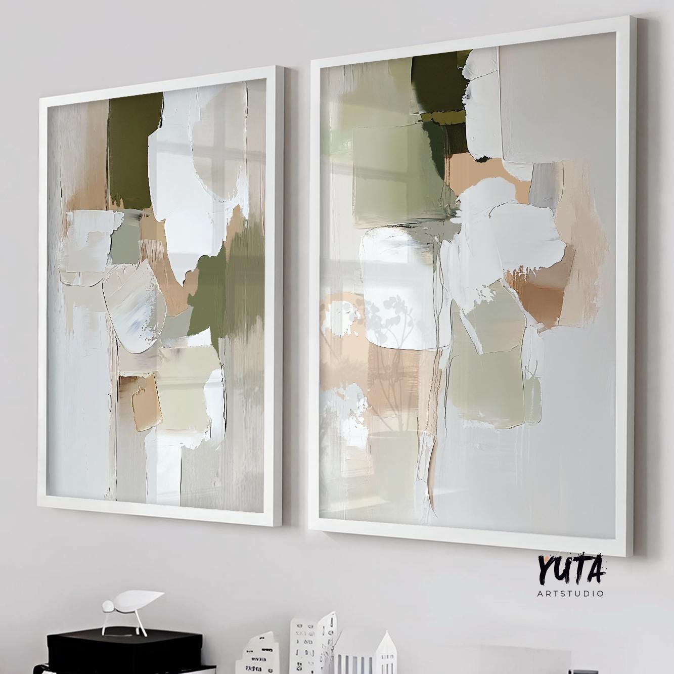 Framed abstract brush stroke art pair in olive, beige, and white hues on a light wall