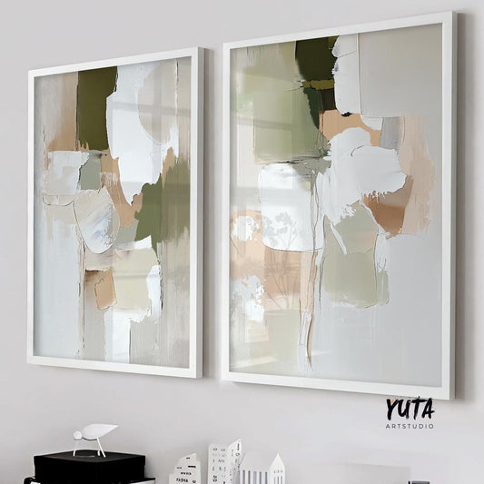 Framed abstract brush stroke art pair in olive, beige, and white hues on a light wall