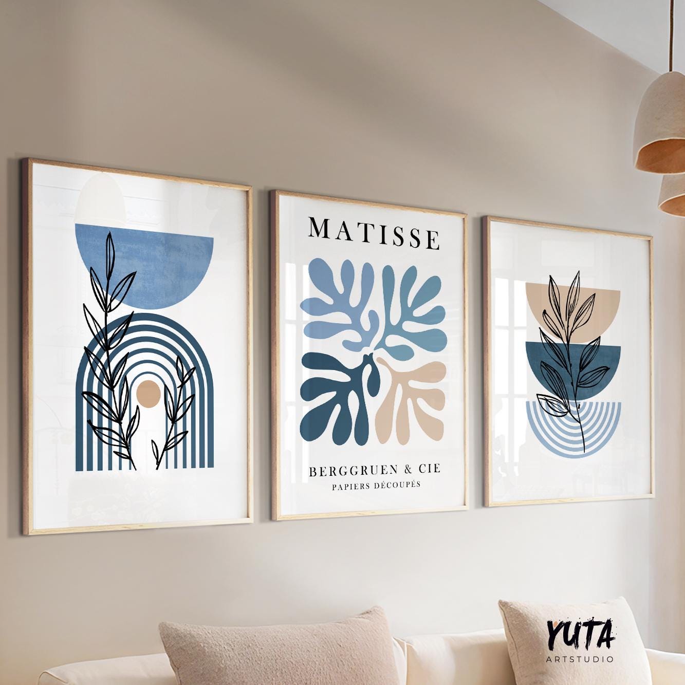 Three framed blue and beige abstract botanical prints arranged above a neutral sofa