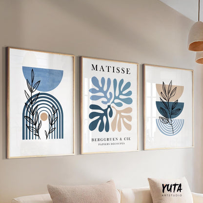 Three framed blue and beige abstract botanical prints arranged above a neutral sofa