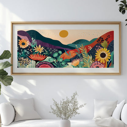 Colorful abstract mountain and floral artwork in a light wood frame above a white sofa
