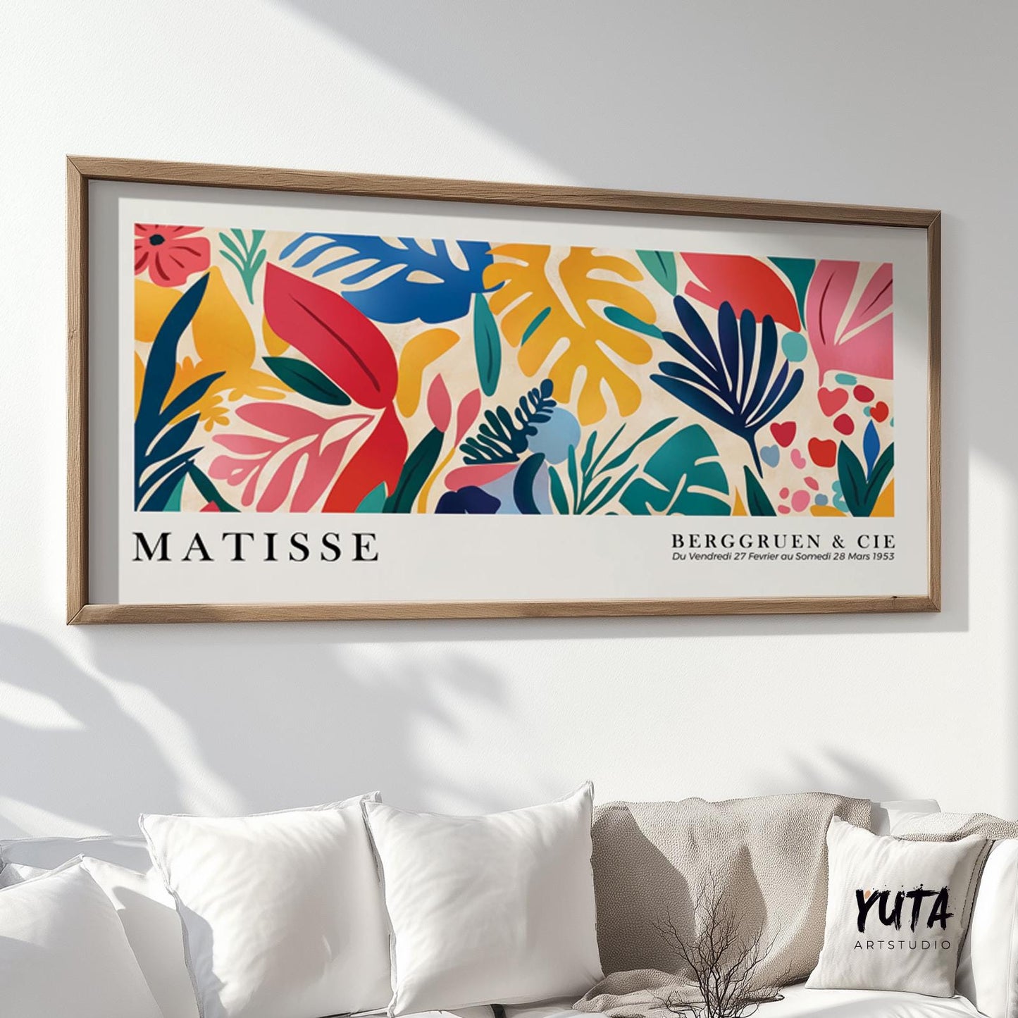 Tropical leaf cut-out artwork in vivid colors, framed and hung above a white sofa