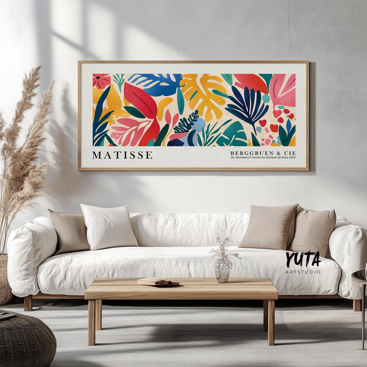 Vibrant abstract tropical leaves artwork in natural wood frame centered above a white sofa