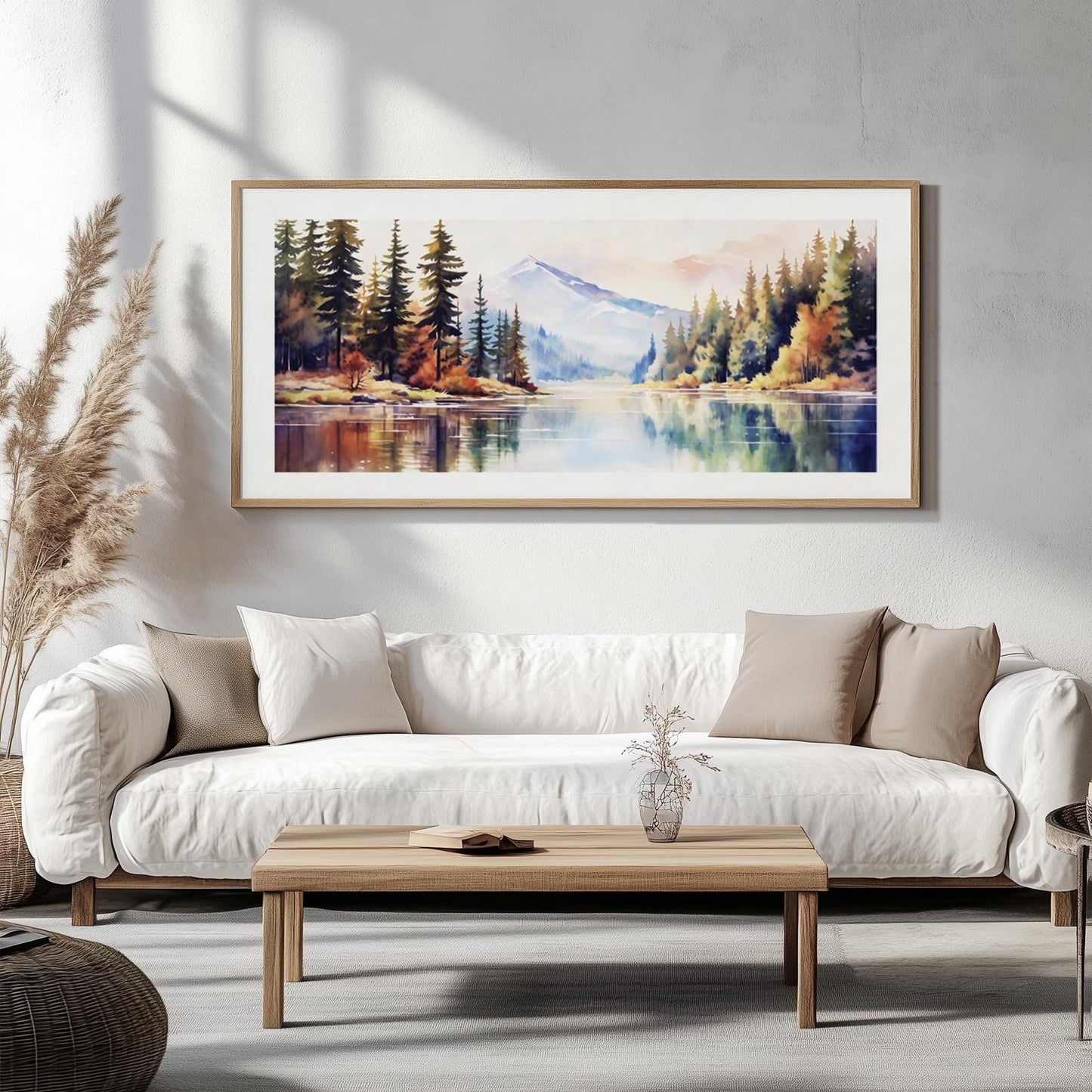 Panoramic framed mountain landscape art hung above a white sofa in a bright living room