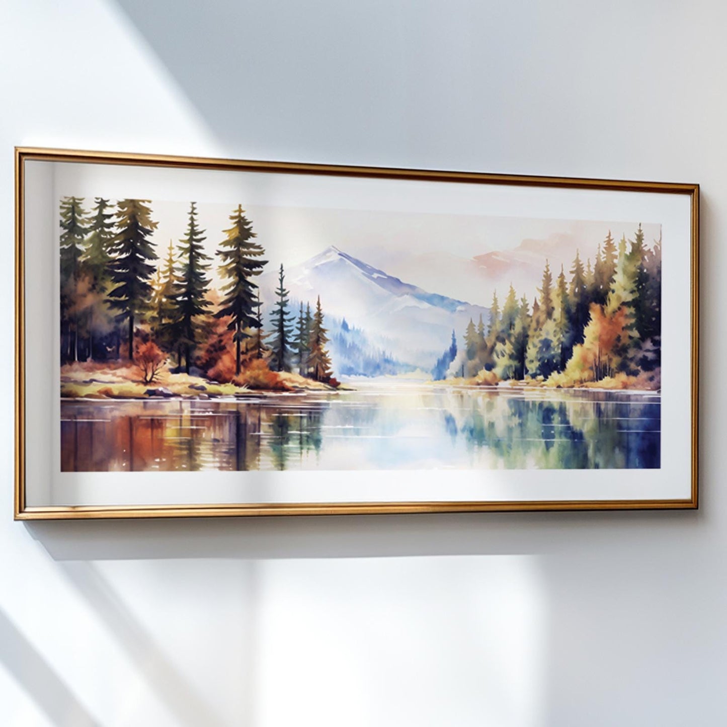 Mountain landscape watercolor in a panoramic gold frame, hung on a sunlit wall