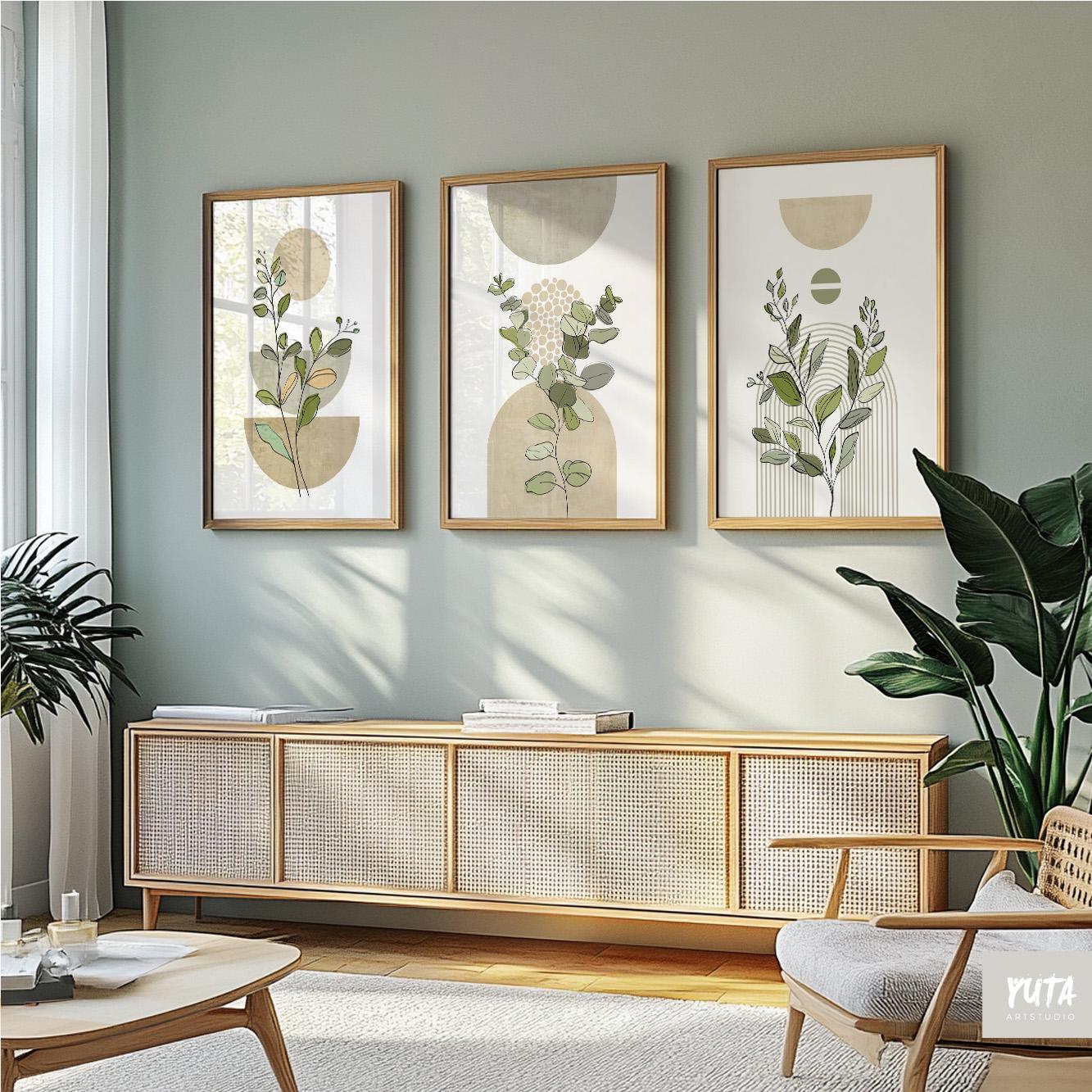 Sage green abstract botanical prints in natural wood frames arranged above a sideboard.