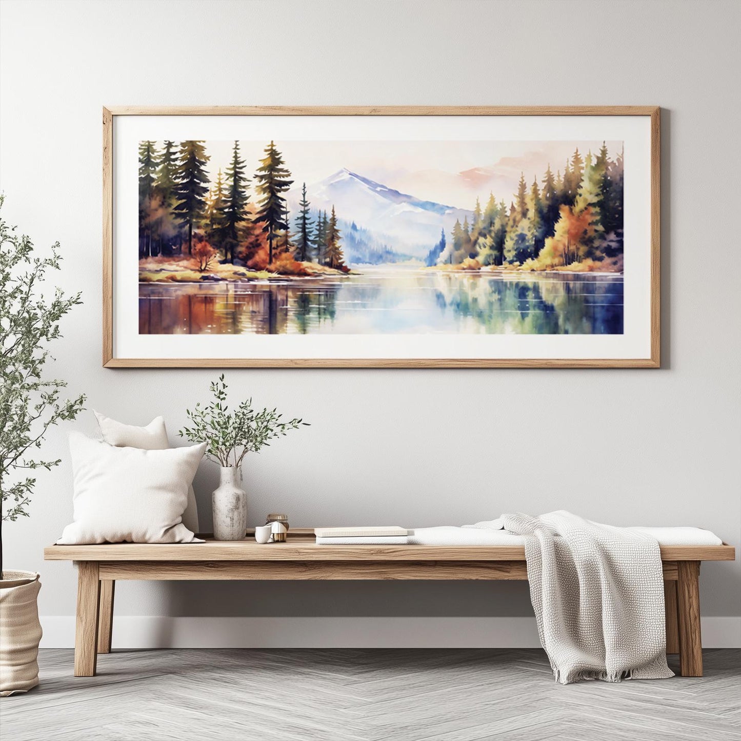 Panoramic watercolor mountain landscape in a light wood frame above a minimalist bench