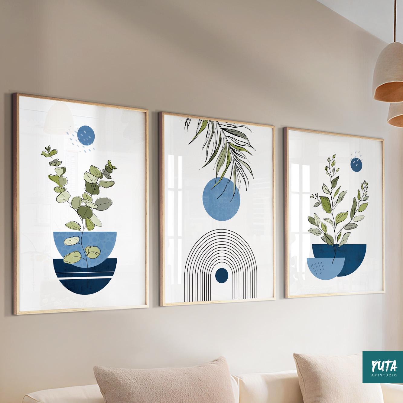 Trio of framed navy blue abstract botanical prints arranged above a cream sofa with books and plants nearby.