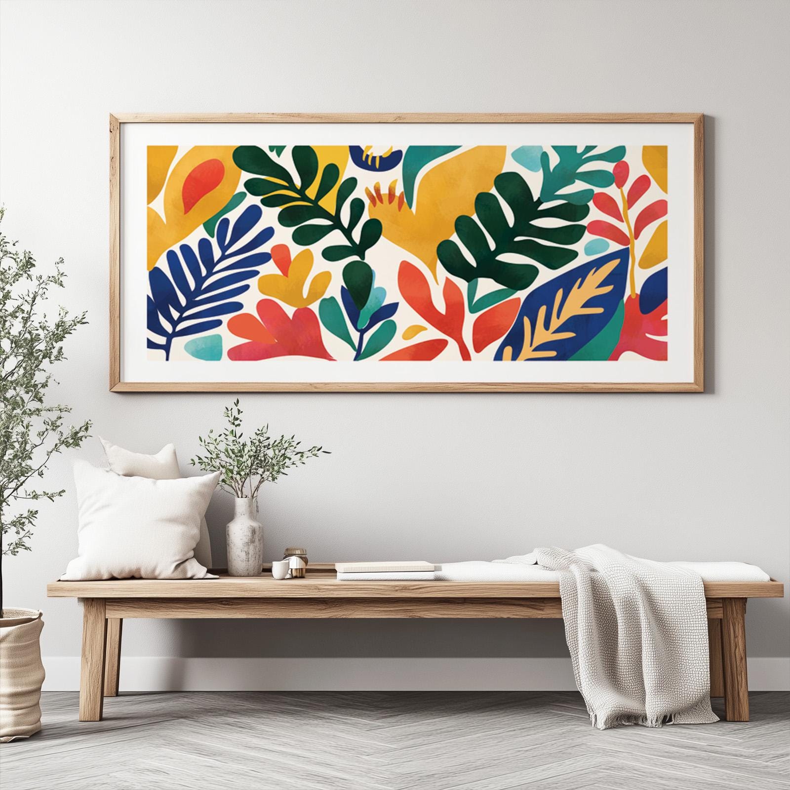 Large framed Matisse-inspired leaf print in bold colors above a wooden bench with plants and books