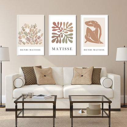Abstract Matisse-inspired art trio in white frames showcased above a glass console.