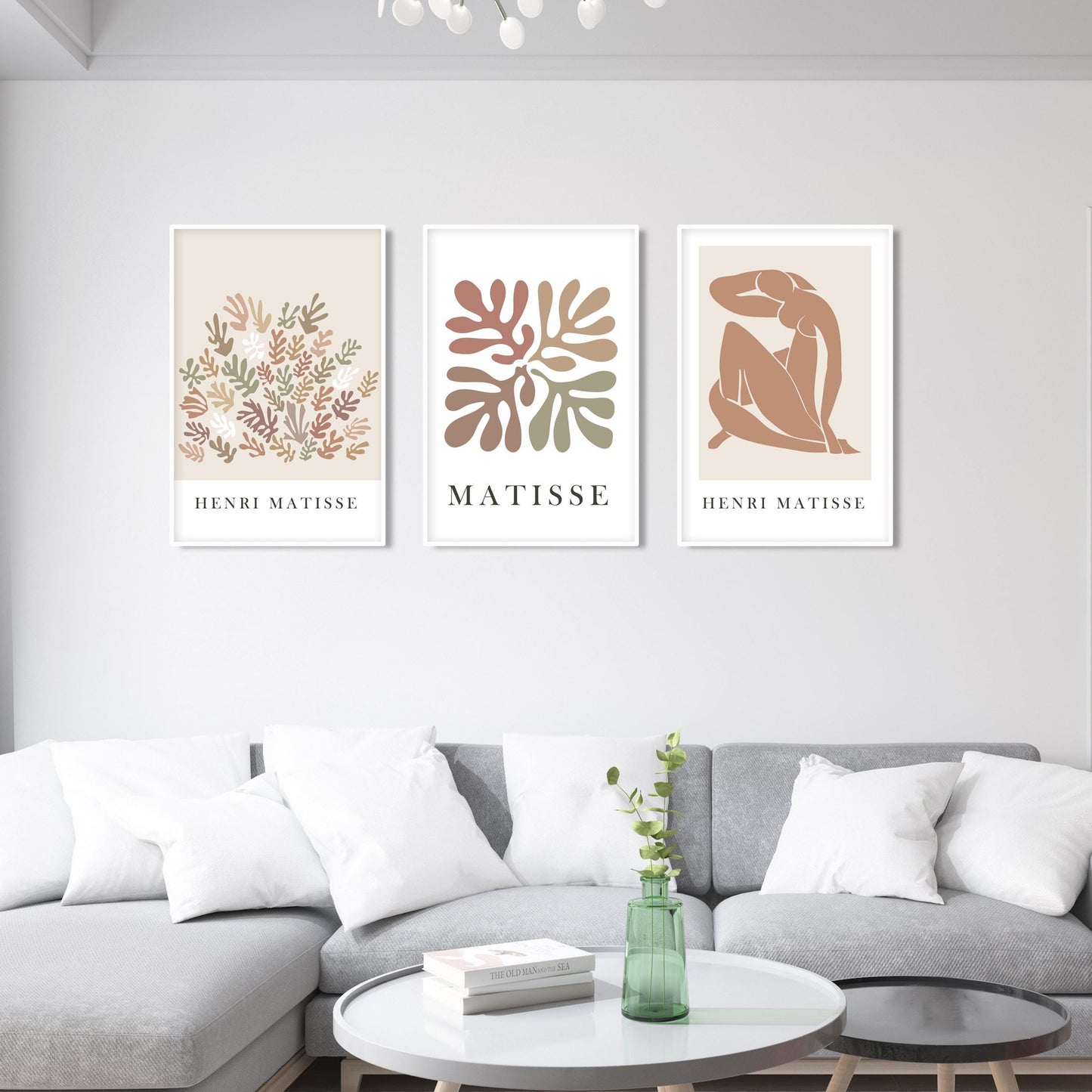 Trio of framed abstract Matisse prints above a sofa, styled with books and a plant.