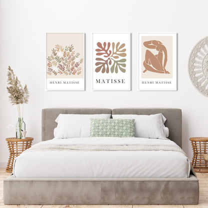 Neutral Matisse art trio in white frames displayed above a taupe velvet bed
