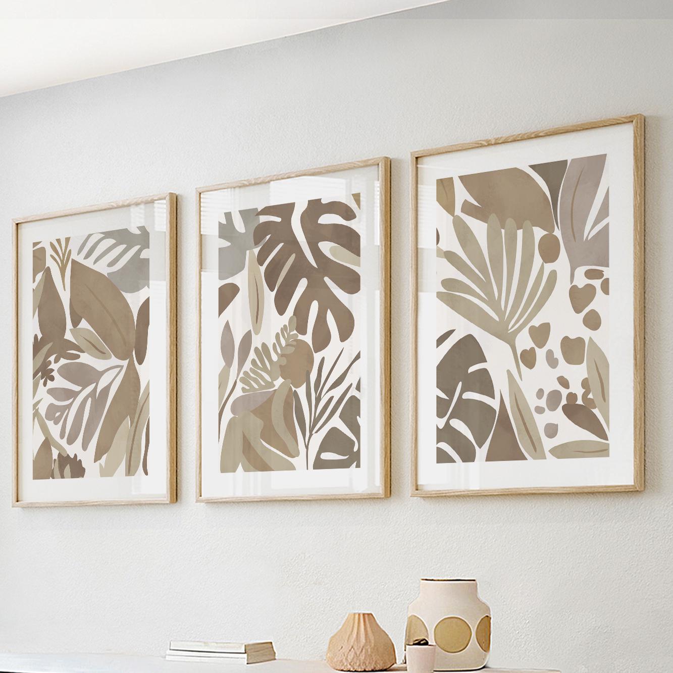 Set of three minimalist mocha tropical prints in light wood frames, grouped above a console.