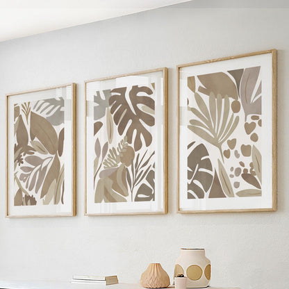 Set of three minimalist mocha tropical prints in light wood frames, grouped above a console.